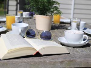 un libro abierto con gafas de sol y una taza de café sobre una mesa en Stechelhus Doppelhaushälfte, en Gross Schwansee