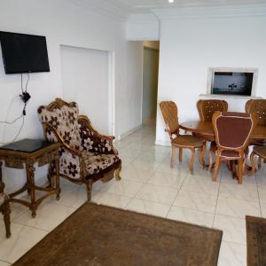 ein Wohnzimmer mit Stühlen, einem Tisch und einem TV in der Unterkunft الاسكندريه خالد بن الوليد in Alexandria