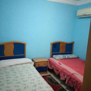 2 Betten in einem Zimmer mit blauen Wänden in der Unterkunft الاسكندريه خالد بن الوليد in Alexandria