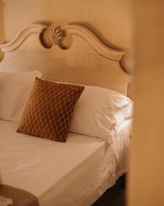 a white bed with a brown pillow on it at Hotel Oviv dimora del borgo in Acquaviva Picena