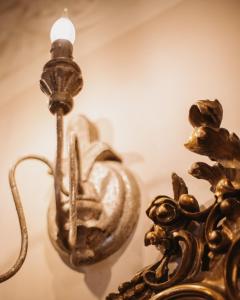 a brass light fixture next to a mirror at Hotel Oviv dimora del borgo in Acquaviva Picena