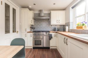 cocina con armarios blancos, fogones y fregadero en Cosy Roseburn Apartment, Edinburgh - 2 Bedrooms, FREE PARKING, en Edimburgo