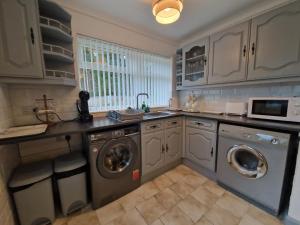 uma cozinha com máquina de lavar e secar roupa em Lakeside 3 Bedroom Bungalow Retreat Merthyr Tydfil em Cefn-coed-y-cymmer