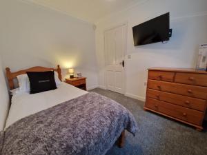 um quarto com uma cama, uma cómoda e uma televisão em Lakeside 3 Bedroom Bungalow Retreat Merthyr Tydfil em Cefn-coed-y-cymmer