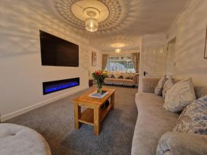 uma sala de estar com um sofá, uma televisão e uma mesa em Lakeside 3 Bedroom Bungalow Retreat Merthyr Tydfil em Cefn-coed-y-cymmer