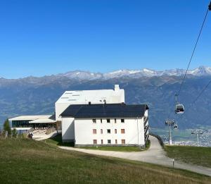 a white building on a hill with a ski lift at Kronplatz Mountain Lodge in Brunico