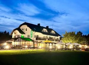 um grande edifício com mesas e guarda-sóis à noite em Butenas Hotel Tyla em Biržai