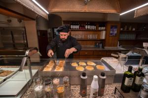 Hotel Marco Polo في لا ماسانا: رجل في مطبخ يعمل الكعك على منضدة