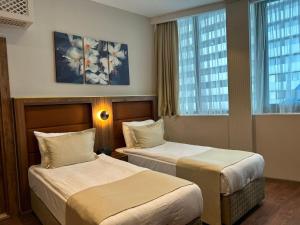 a hotel room with two beds and two windows at Sky Tower Hotel in Batumi