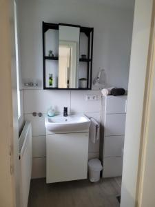 a white bathroom with a sink and a mirror at Ferienhaus Gertrud in Nesselwängle