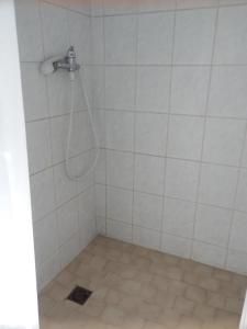 a shower with a hose in a white tiled bathroom at Ubytovna u hospůdky in Ostrava