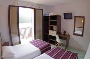 a hotel room with two beds and a desk and a window at Brise de Mer in Porto Ota