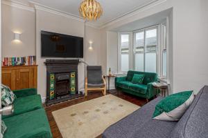 a living room with a green couch and a fireplace at Character Townhouse in Town Centre & Superb Views in Dolgellau