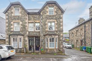 an old stone house with cars parked in front of it at Character Townhouse in Town Centre & Superb Views in Dolgellau