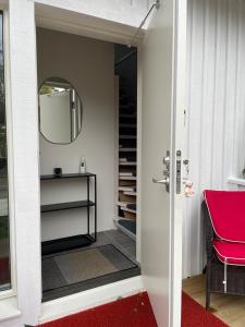 a door to a room with a red chair and a mirror at Charmig apartens in à house in stockholm in Stockholm