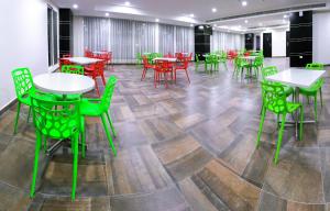ein Zimmer mit Tischen, Stühlen und grünen Stühlen in der Unterkunft Amber Tower in Al Ghurayfah
