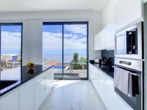 a kitchen with white cabinets and a view of the ocean at Casa das Flores by LovelyStay in Calheta