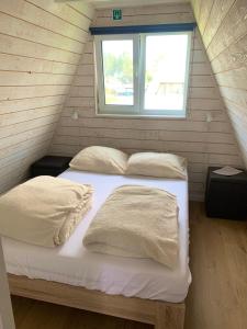 two beds in a small room with a window at Dunenestje in Oostduinkerke
