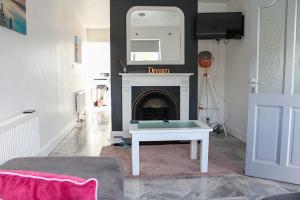 a living room with a fireplace with a table in front of it at 2 BEDROOM The White House in Cahersiveen