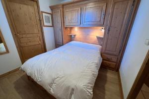 a small bedroom with a bed and wooden cabinets at Les Granges 13 6-8 person in Aime-La Plagne