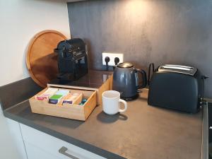 una encimera con cafetera y una taza sobre una mesa en MOKA Living eWald - 2Zi Apartment-FeWo, E-Charger, Barrierearm, Boxspring, TV en Borkheide