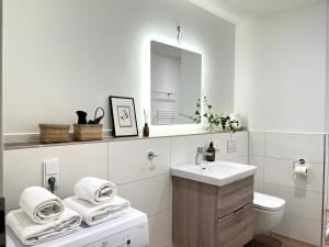 Baño blanco con lavabo y espejo en MOKA Living eWald - 2Zi Apartment-FeWo, E-Charger, Barrierearm, Boxspring, TV, en Borkheide