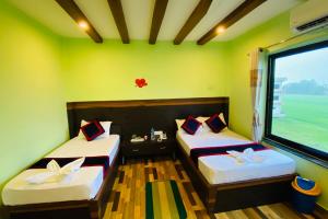 Cette chambre comprend 2 lits dans une chambre dotée de murs verts et d'une fenêtre. dans l'établissement The Lumbini Hotel, à Rummindei