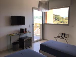 1 dormitorio con 1 cama, TV y ventana en Suite avec 2 chambres d'hôtes pour 1 à 4 personnes avec terrasse, vue mer, parking privé, proche port et aéroport en Ajaccio