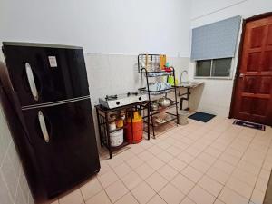 a kitchen with a black refrigerator and a tile floor at Fausal Legacy Homestay Sungai Besar in Sungai Besar