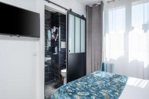 a room with a tv and a bed and a bathroom at The Originals Boutique, Hôtel Le Marignan,Le Havre Centre Gare in Le Havre