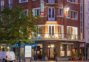 ein Gebäude auf einer Straße mit einem Van vor dem Haus in der Unterkunft The Originals Boutique, Hôtel Le Marignan,Le Havre Centre Gare in Le Havre