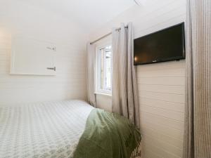 een kleine slaapkamer met een bed en een flatscreen-tv bij Hazel in Cirencester
