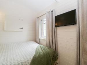 Beech في Kemble: غرفة نوم صغيرة بها سرير وتلفزيون بشاشة مسطحة