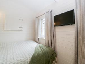 a small bedroom with a bed and a flat screen tv at Willow in Kemble