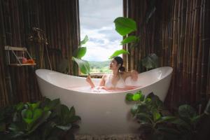 a woman sitting in a bath tub in a bathroom at Paopao Orange Farm and Home stay in Mae Rim