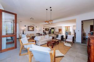 a living room with white couches and a dining room at Karabai Villa in Matemwe