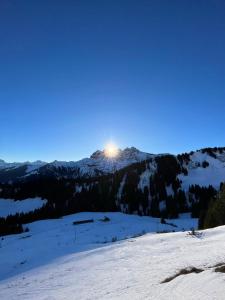 a view of a snow covered mountain with the sun in the sky at Chalet LYS Apartment 14 Rue Sigma in Champoussin