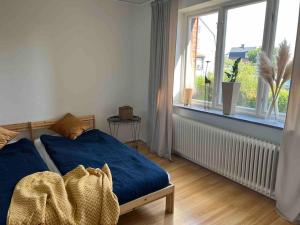 a bedroom with a blue bed and a window at KvarteretSkatan! in Ystad