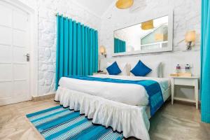 a bedroom with a large bed with blue curtains at The Tamarind Hotel Goa in Anjuna