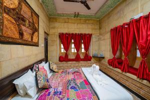 kings villa Jaisalmer في جيلسامر: غرفة نوم بسرير كبير وستائر حمراء
