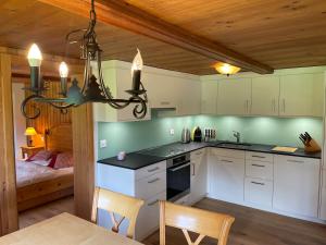 a kitchen with white cabinets and a chandelier at Weissmies Lodge in Saas-Grund