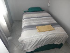 a twin sized bed with a yellow towel on it at Las Palmas Day & Night Guest House in Pretoria