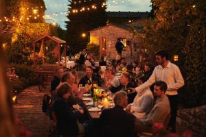 a group of people sitting at a table in a garden at Borgo Vescine in Radda in Chianti