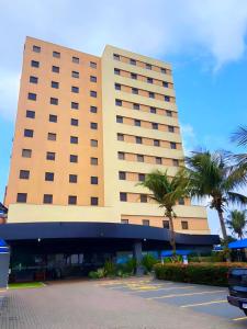 um grande edifício com palmeiras em frente em Hotel Thomasi Express em Maringá