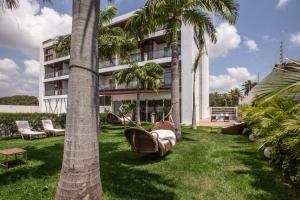 a hotel with palm trees and a hammock in the yard at Hotel de Luxo Tango Suites & Coworking Cumbuco in Cumbuco