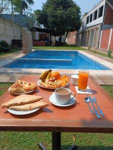 a table with breakfast foods and drinks and a pool at Ullanka Apart Hotel in Encarnación