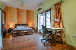 a bedroom with a bed and a desk and a window at HomeSlice Manor in Bangalore