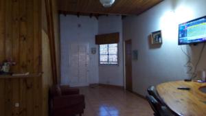 een woonkamer met een houten tafel en een televisie bij Casa planta baja en Faro Mogotes in Mar del Plata