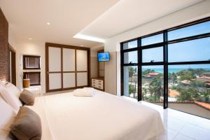 um quarto com uma cama branca e uma grande janela em Hotel de Luxo Tango Suites & Coworking Cumbuco em Cumbuco