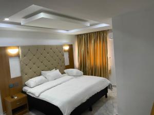 1 dormitorio con 1 cama grande con sábanas y almohadas blancas en DND Apartments, en Benin City